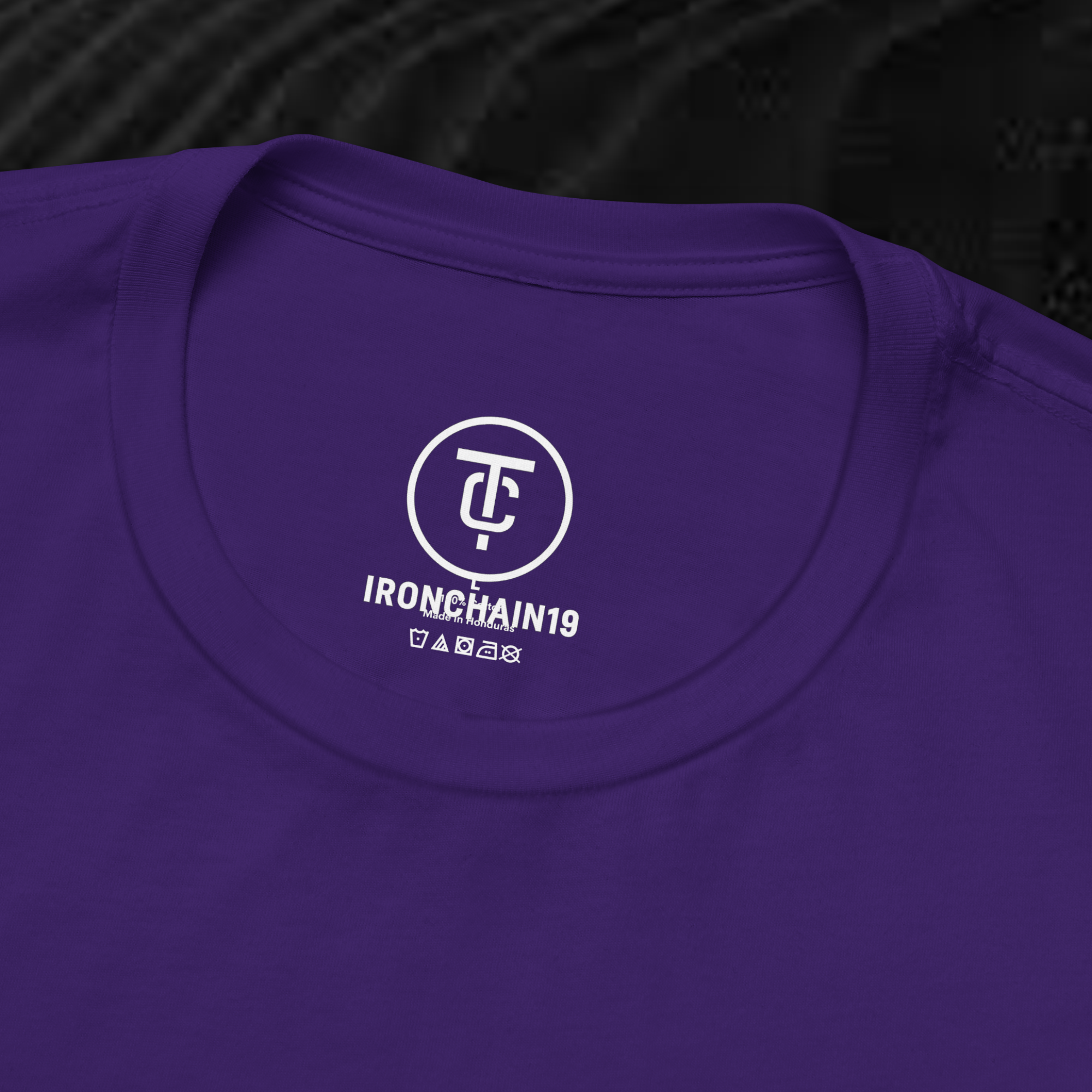 A close-up of the inside collar of a  cotton t-shirt from Ironchain 19. The tagless printed label features a sleek white logo with a chain illustration, surrounded by number19 . Below the logo, the text indicates the shirt is 100% cotton, made in Bangladesh, and includes washing care symbols. The soft fabric and seamless neckline highlight the premium quality and comfort of this Gothic aesthetics  perfect for cat lovers and fans of modern streetwear fashion.