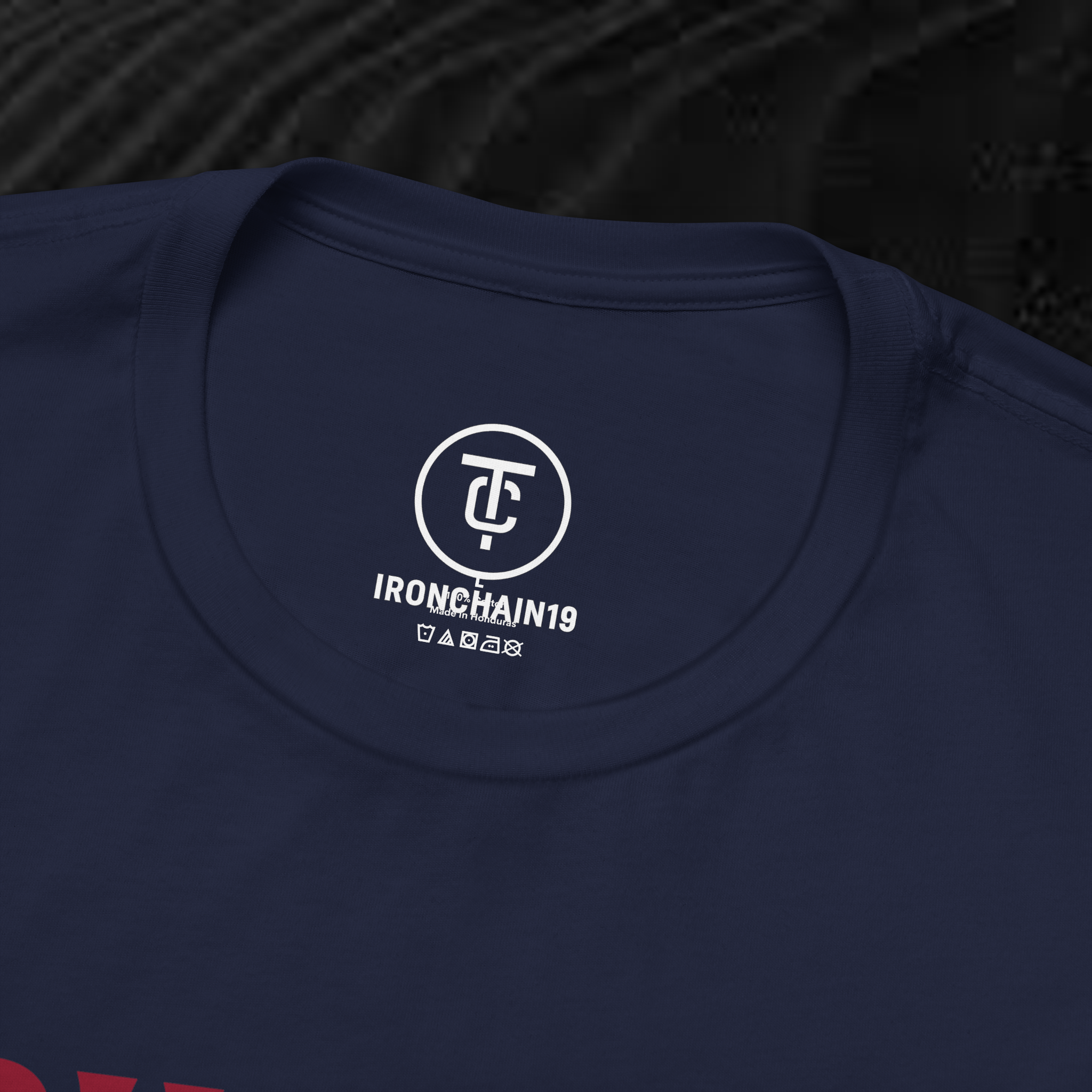 A close-up of the inside collar of a  cotton t-shirt from Ironchain 19. The tagless printed label features a sleek white logo with a chain illustration, surrounded by number19 . Below the logo, the text indicates the shirt is 100% cotton, made in Bangladesh, and includes washing care symbols. The soft fabric and seamless neckline highlight the premium quality and comfort of this Gothic aesthetics  perfect for cat lovers and fans of modern streetwear fashion.