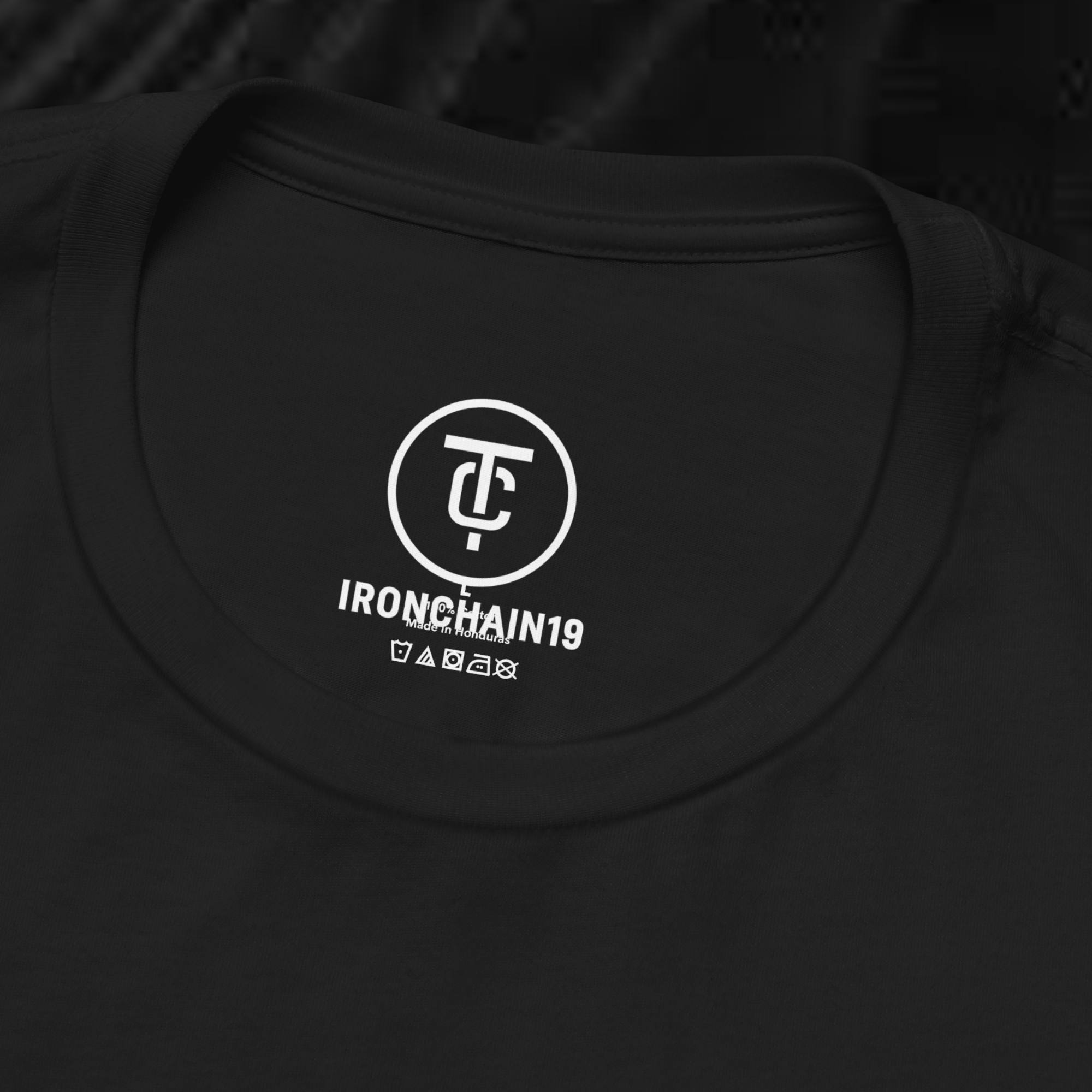 A close-up of the inside collar of a  cotton t-shirt from Ironchain 19. The tagless printed label features a sleek white logo with a chain illustration, surrounded by number19 . Below the logo, the text indicates the shirt is 100% cotton, made in Bangladesh, and includes washing care symbols. The soft fabric and seamless neckline highlight the premium quality and comfort of this Gothic aesthetics  perfect for cat lovers and fans of modern streetwear fashion.