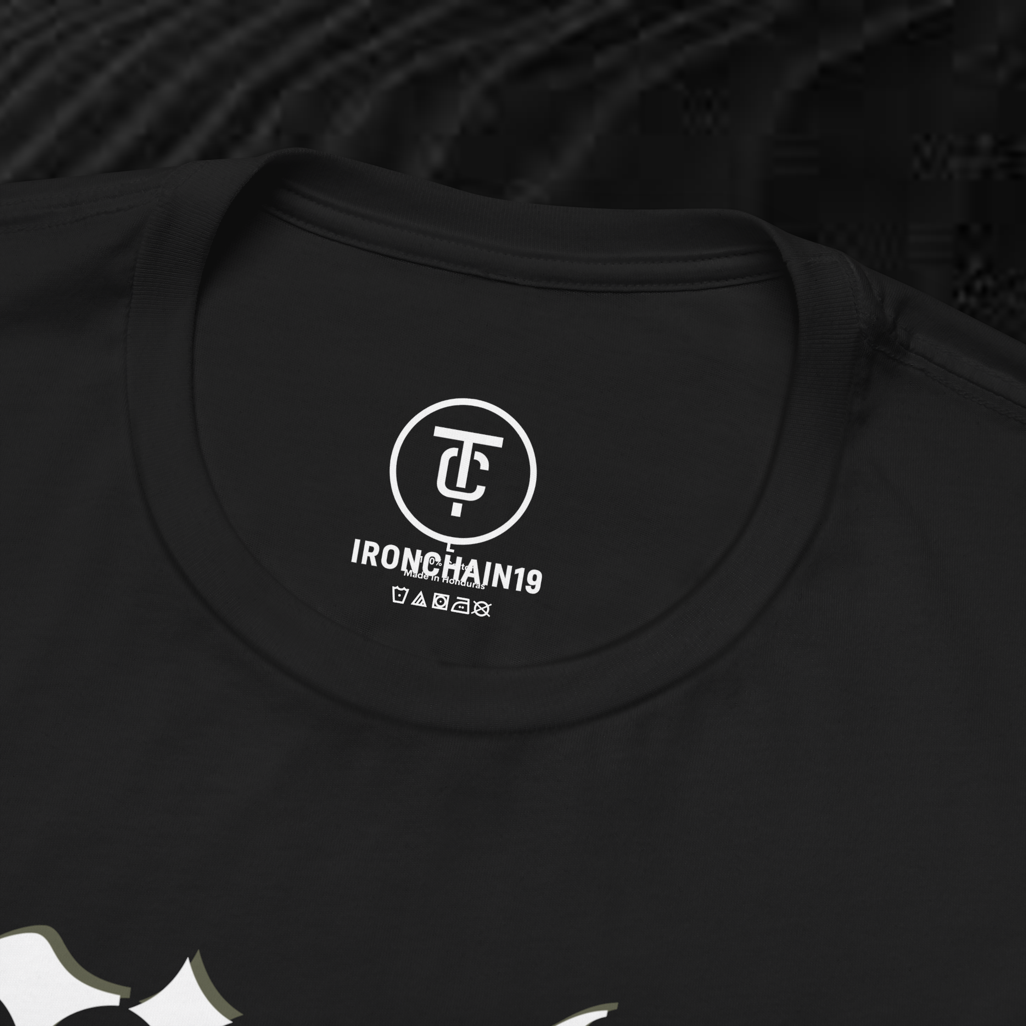 A close-up of the inside collar of a  cotton t-shirt from Ironchain 19. The tagless printed label features a sleek white logo with a chain illustration, surrounded by number19 . Below the logo, the text indicates the shirt is 100% cotton, made in Bangladesh, and includes washing care symbols. The soft fabric and seamless neckline highlight the premium quality and comfort of this Gothic aesthetics  perfect for cat lovers and fans of modern streetwear fashion.