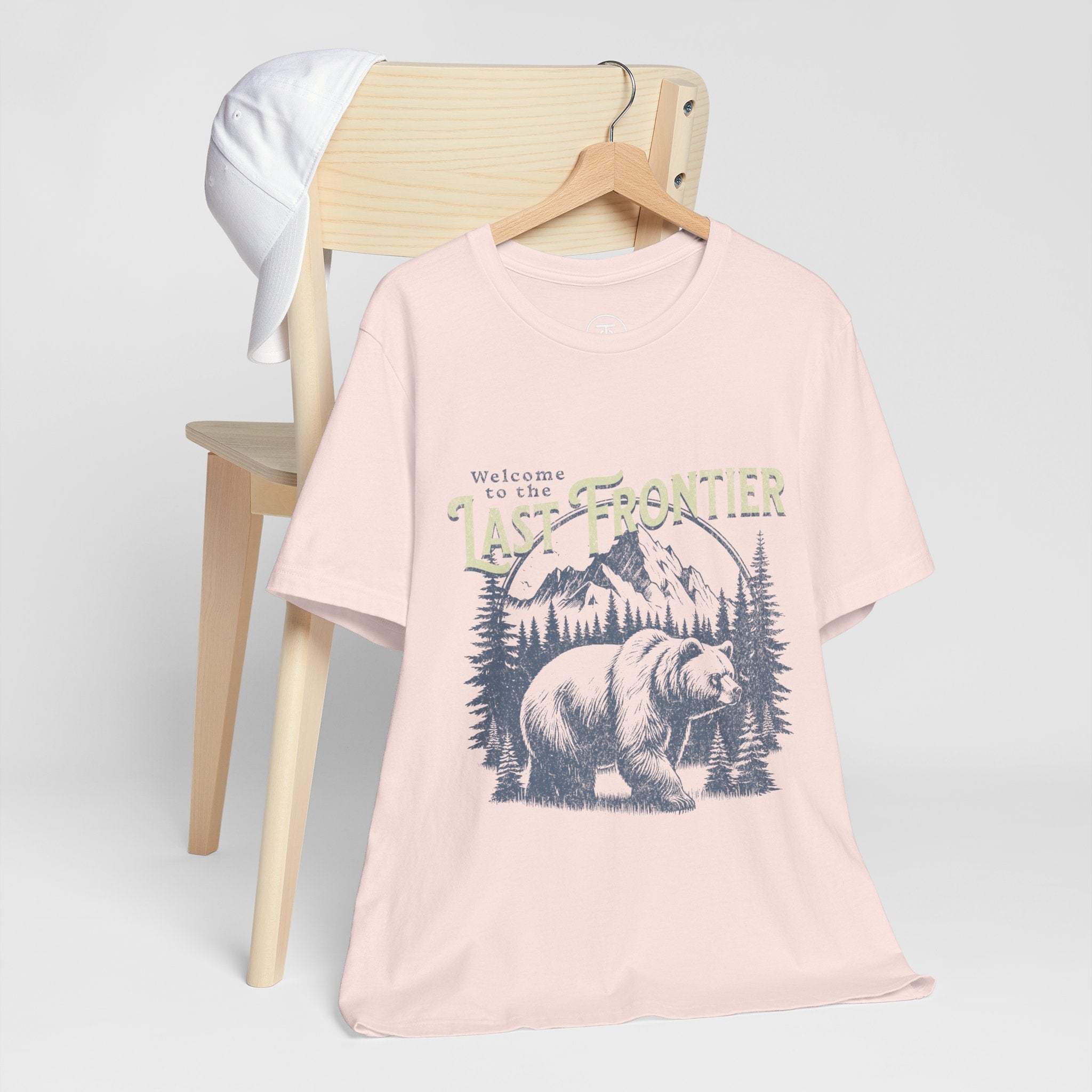 "Alaska adventure shirt with bear illustration and rugged nature backdrop"
